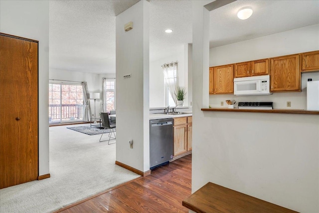 1229 Clarence St, Saint Paul, MN 55106 - kitchen featuring stainless steel dishwasher, white microwave, stove, dark wood-style floors, and dark carpet