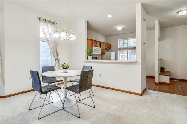 carpeted dining room featuring a notable chandelier