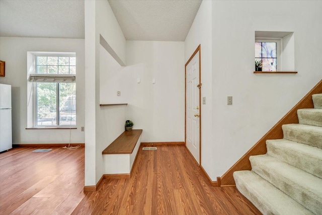 1229 Clarence St, Saint Paul, MN 55106 - corridor with wood finished floors, stairway, baseboards, and a textured ceiling