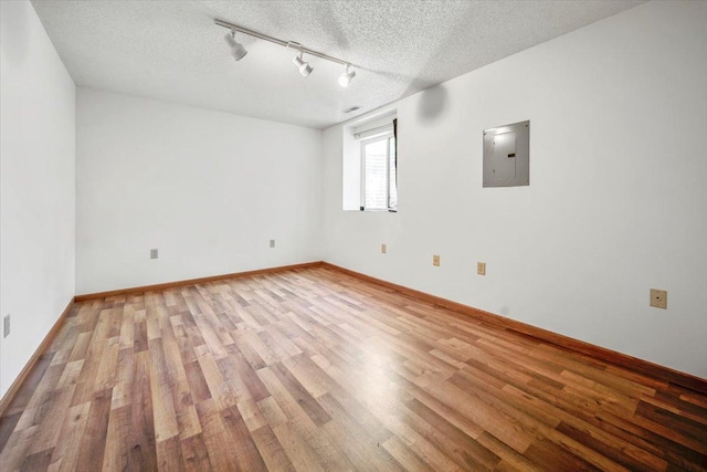1229 Clarence St, Saint Paul, MN 55106 - spare room featuring electric panel, light wood-style flooring, track lighting, a textured ceiling, and baseboards