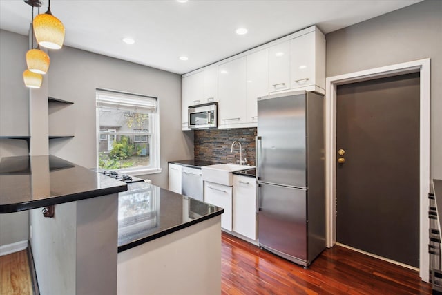 kitchen featuring sink, dark hardwood / wood-style flooring, white cabinetry, stainless steel appliances, and pendant lighting