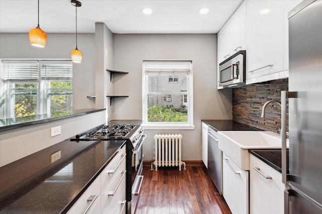 kitchen featuring plenty of natural light, white cabinetry, radiator heating unit, and stainless steel appliances