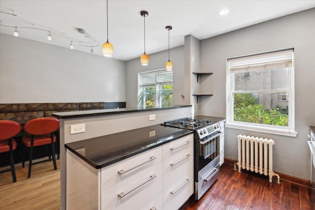 kitchen featuring kitchen peninsula, white cabinetry, stainless steel stove, radiator, and dark wood-type flooring