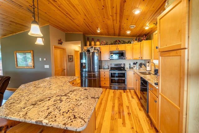 kitchen with lofted ceiling, sink, hanging light fixtures, appliances with stainless steel finishes, and light stone countertops