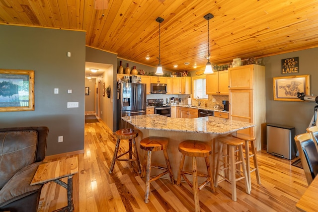 kitchen featuring vaulted ceiling, appliances with stainless steel finishes, pendant lighting, sink, and light brown cabinets