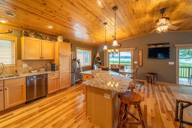 kitchen featuring a kitchen island, appliances with stainless steel finishes, light brown cabinetry, decorative light fixtures, and sink