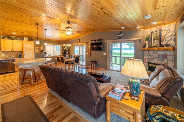 living room featuring vaulted ceiling, a stone fireplace, ceiling fan with notable chandelier, light hardwood / wood-style floors, and wooden ceiling