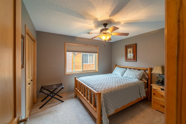 bedroom featuring ceiling fan, light colored carpet, and a textured ceiling