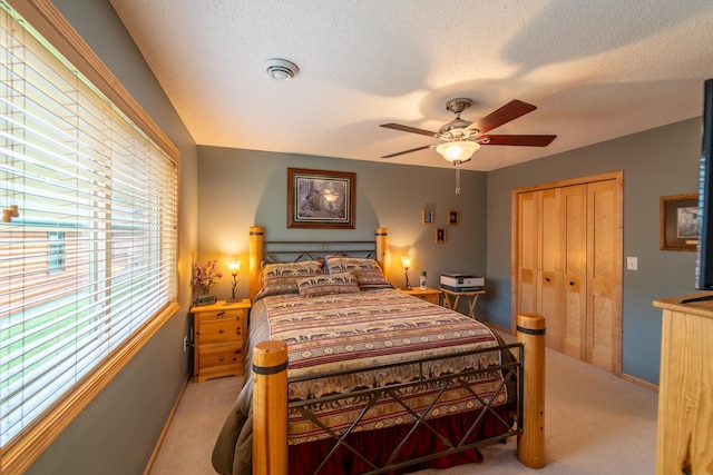 carpeted bedroom featuring ceiling fan, a textured ceiling, and a closet