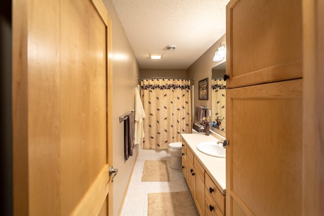 bathroom with tile patterned flooring, vanity, a textured ceiling, and toilet