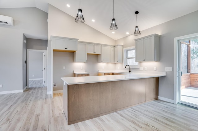 kitchen featuring light wood-type flooring, kitchen peninsula, plenty of natural light, and decorative light fixtures