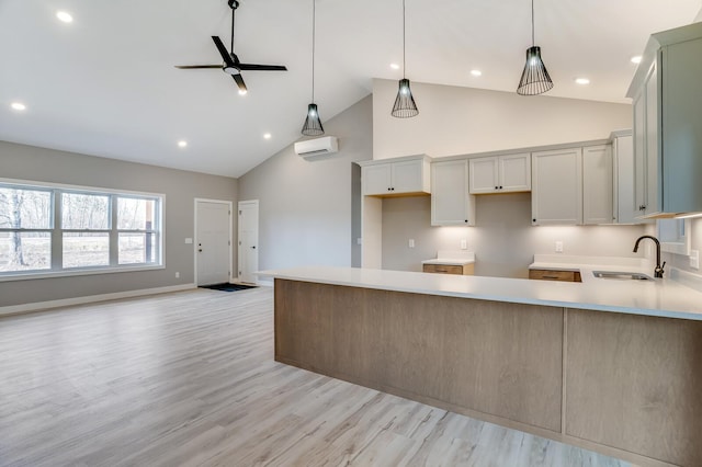 kitchen featuring ceiling fan, hanging light fixtures, sink, light hardwood / wood-style flooring, and high vaulted ceiling