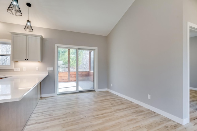 interior space featuring lofted ceiling, light hardwood / wood-style flooring, and decorative light fixtures