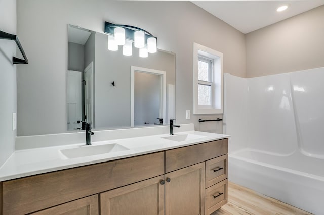 bathroom featuring wood-type flooring, washtub / shower combination, and vanity