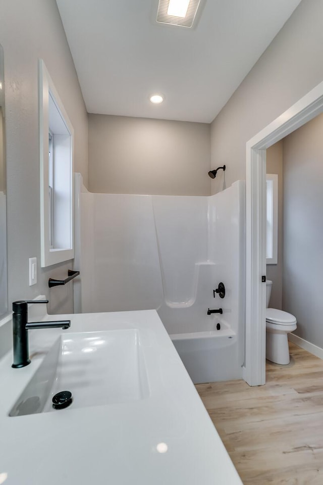 full bathroom with hardwood / wood-style floors, tub / shower combination, toilet, and sink