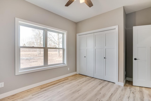 unfurnished bedroom featuring multiple windows, ceiling fan, light hardwood / wood-style flooring, and a closet