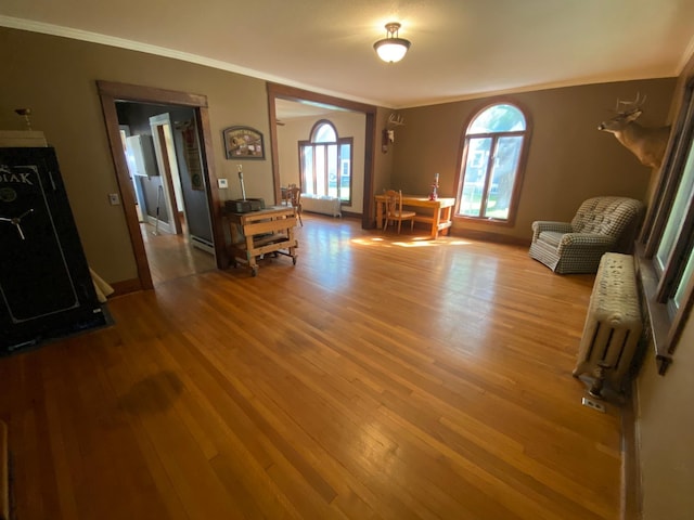 living room featuring radiator, hardwood / wood-style floors, a baseboard heating unit, and crown molding