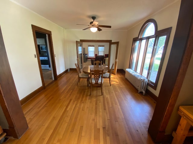 dining area featuring light hardwood / wood-style floors, a wealth of natural light, ceiling fan, and radiator heating unit