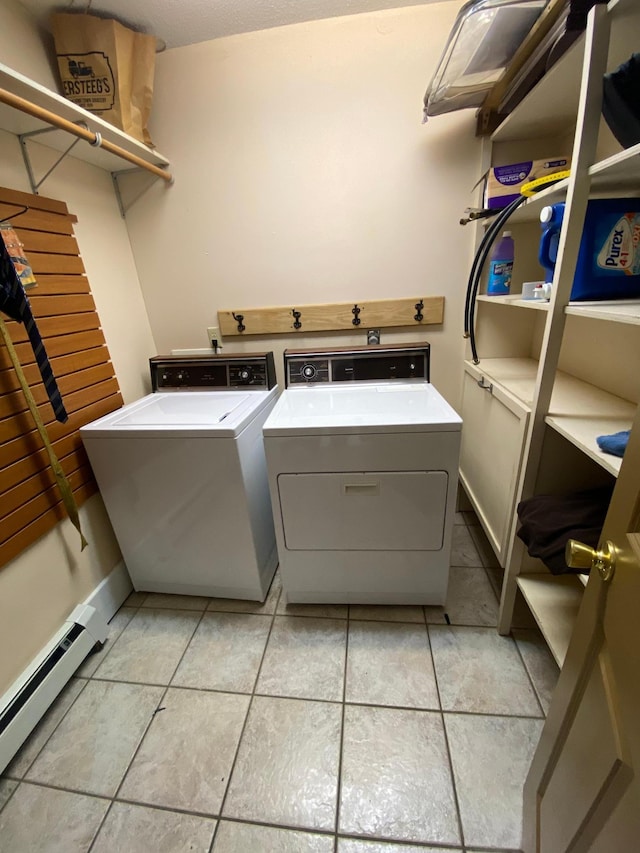 clothes washing area with light tile patterned floors, washing machine and clothes dryer, and baseboard heating