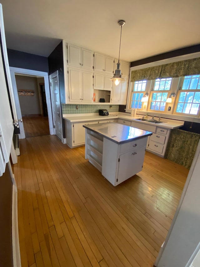 kitchen with sink, light wood-type flooring, decorative light fixtures, and a kitchen island