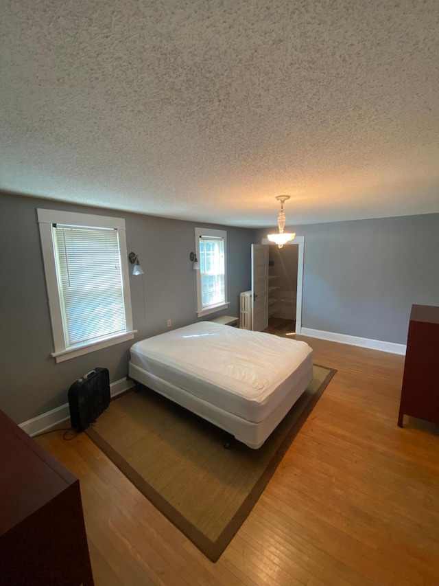 bedroom featuring hardwood / wood-style flooring, a textured ceiling, and radiator