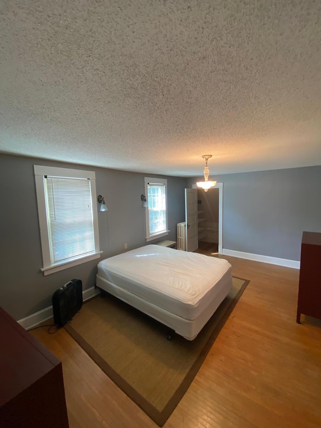 bedroom featuring a textured ceiling, radiator, and hardwood / wood-style floors