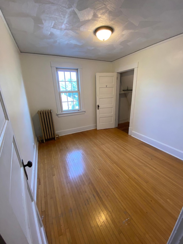 unfurnished bedroom featuring a closet, hardwood / wood-style floors, and radiator