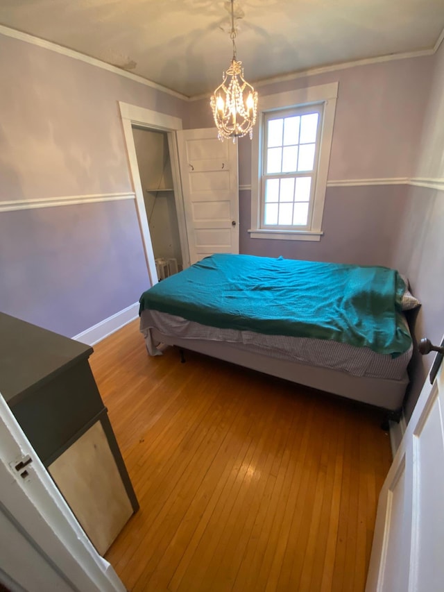 bedroom featuring radiator heating unit, crown molding, an inviting chandelier, and hardwood / wood-style flooring