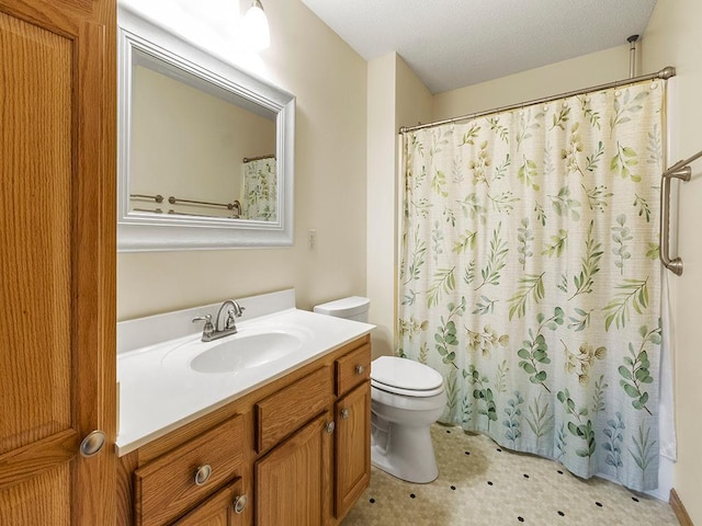 bathroom featuring a textured ceiling, vanity, toilet, and walk in shower