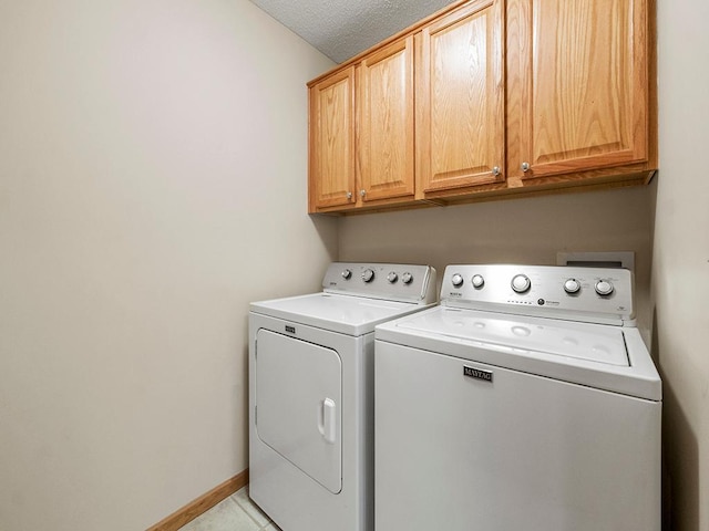 laundry room featuring cabinets, a textured ceiling, washing machine and dryer, and light tile patterned floors