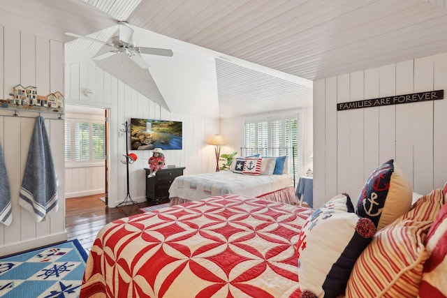 bedroom with ceiling fan, wood ceiling, dark wood-type flooring, and wooden walls