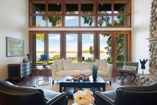 interior space with french doors, a water view, a high ceiling, and hardwood / wood-style flooring