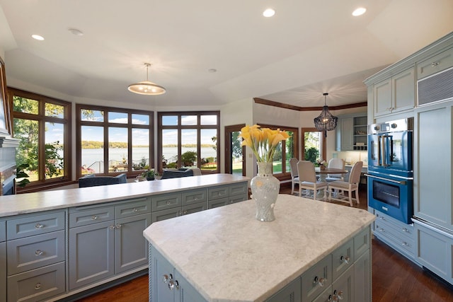 kitchen featuring gray cabinetry, a center island, hanging light fixtures, and double oven