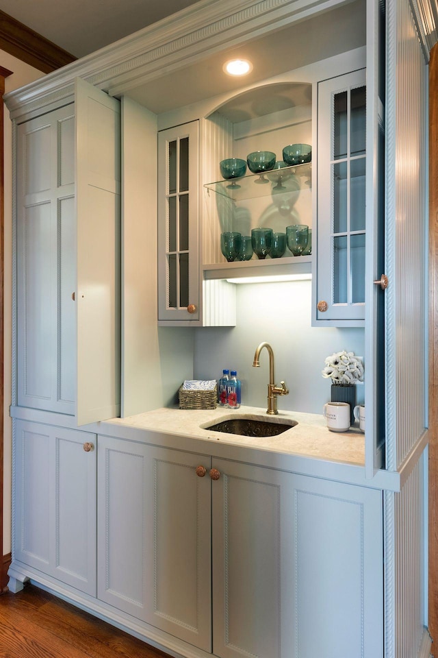 bar with dark hardwood / wood-style floors, white cabinetry, ornamental molding, and sink