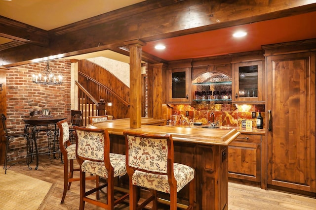 bar featuring beam ceiling, sink, wood counters, light wood-type flooring, and ornamental molding