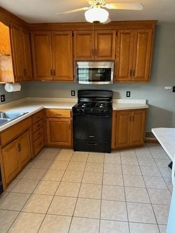 kitchen featuring ceiling fan, sink, gas stove, and light tile patterned flooring