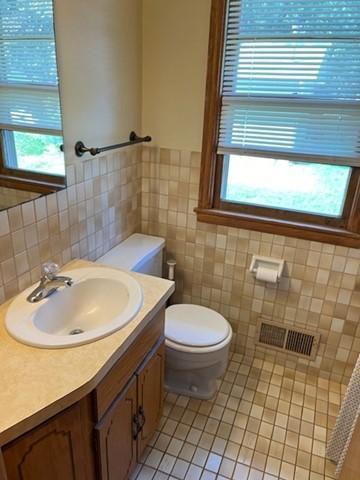 bathroom with plenty of natural light, toilet, vanity, and tile patterned floors