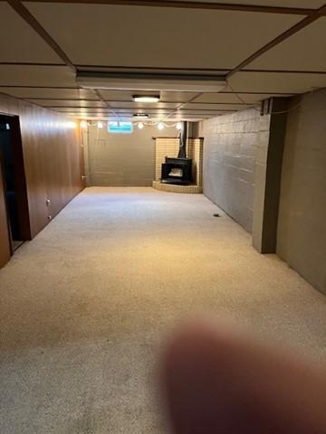 basement featuring a wood stove and carpet flooring