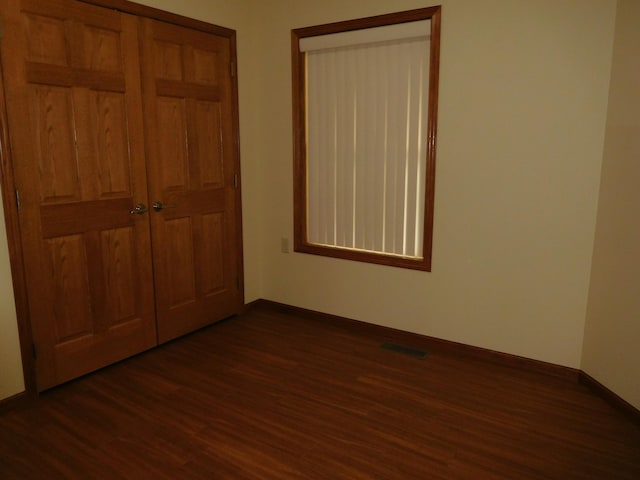 unfurnished bedroom with dark hardwood / wood-style flooring and a closet