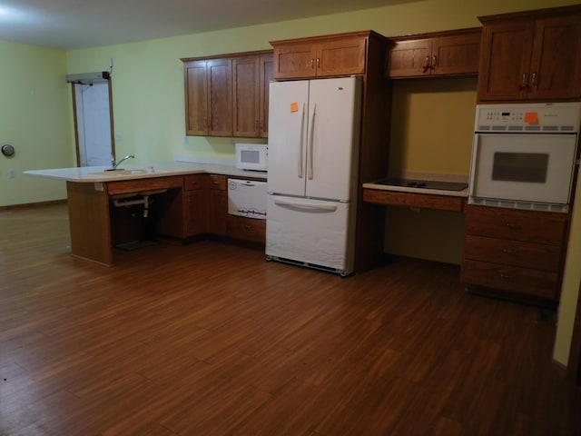 kitchen with kitchen peninsula, dark hardwood / wood-style flooring, white appliances, and sink