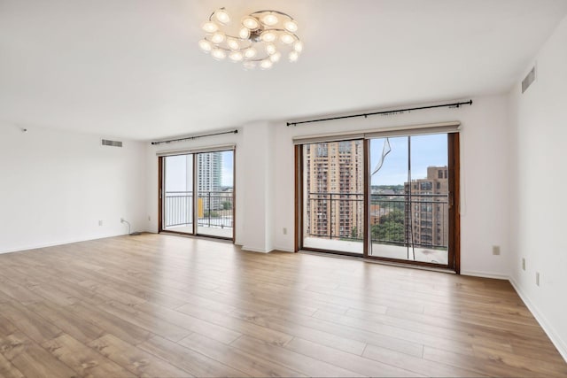 empty room with light wood-type flooring and a chandelier