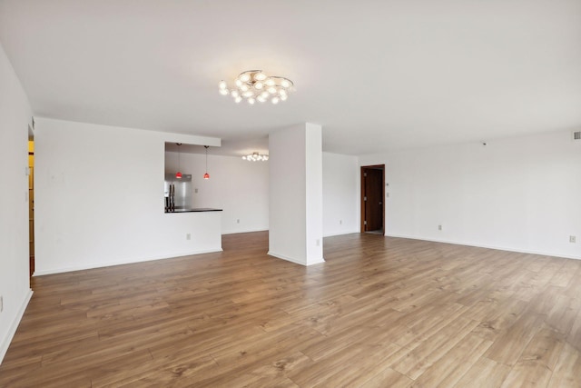 unfurnished living room featuring light hardwood / wood-style flooring and a notable chandelier