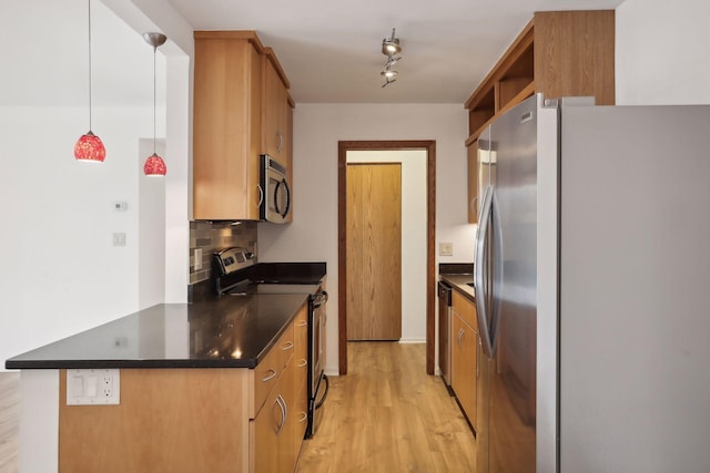 kitchen featuring light wood-type flooring, track lighting, stainless steel appliances, decorative backsplash, and hanging light fixtures