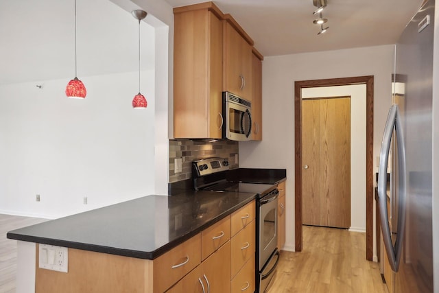 kitchen with light hardwood / wood-style flooring, appliances with stainless steel finishes, rail lighting, pendant lighting, and tasteful backsplash