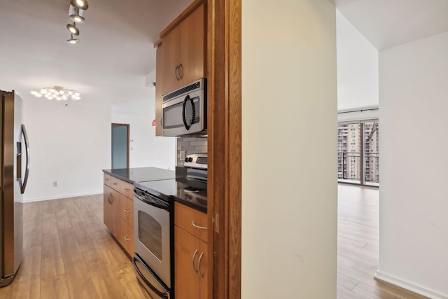 kitchen featuring light wood-type flooring, backsplash, and stainless steel appliances