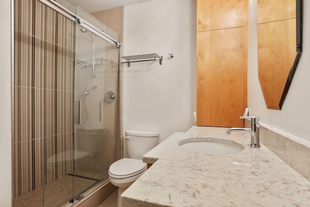 bathroom with toilet, a shower with door, and vanity