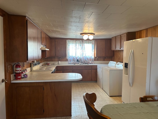 kitchen with white appliances, sink, kitchen peninsula, and washer and dryer