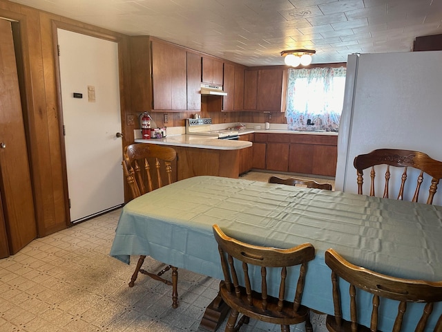 kitchen with stainless steel range oven, kitchen peninsula, sink, and white refrigerator