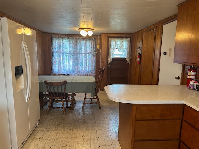 kitchen featuring kitchen peninsula and white fridge with ice dispenser