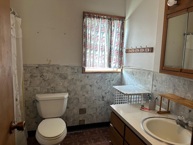 bathroom featuring backsplash, vanity, toilet, and tile walls